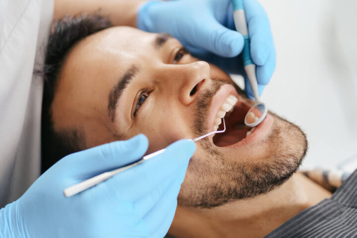Dentist performing a tooth extraction procedure with dental tools in a clinic