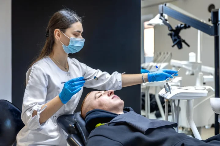 Female dentist treating patient’s teeth using professional dental equipment