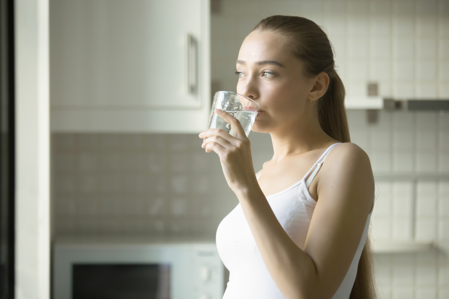 Young girl drinking water for dental implant recovery